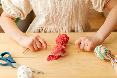 Midsection of woman holding heart shape on table