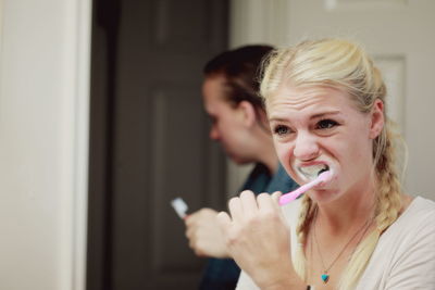 Woman with sibling brushing teeth in bathroom at home