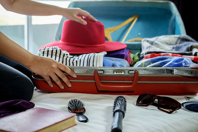 Midsection of woman packing suitcase on bed at home