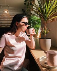 Young woman drinking coffee while sitting at cafe