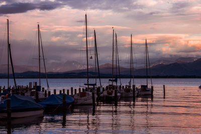 Sailboats moored in sea against sky during sunset