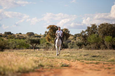 Man riding horse on land against sky