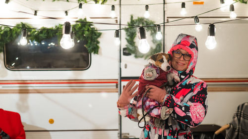 Portrait of woman holding dog while standing by motor home