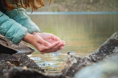 Hand touches the water in the pond. dripping liquid from palms. female hands with splashes of water