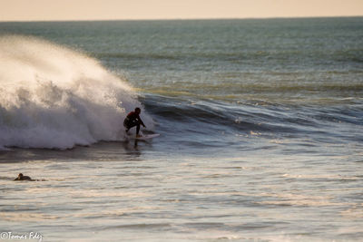 Man surfing in sea against sky