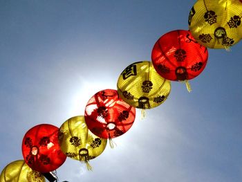 Low angle view of lanterns hanging against sky during sunny day