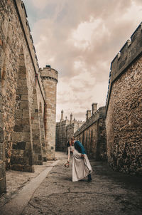 Rear view of woman walking on historical building against sky