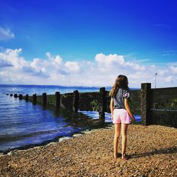 Rear view of woman standing by sea against sky