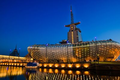 Low angle view of illuminated modern buildings against blue sky at night