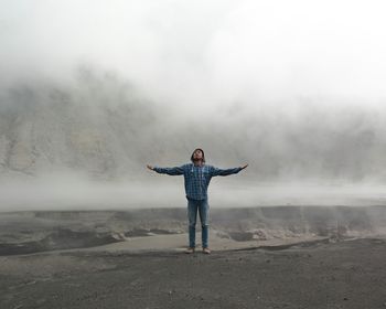 Full length rear view of young woman standing in foggy weather