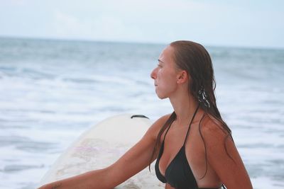 Mid adult woman standing at beach against sky