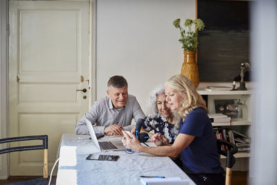 Happy senior male and females vlogging at table in living room