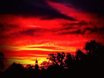 Low angle view of silhouette trees against dramatic sky