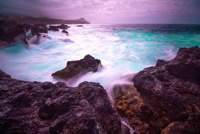 Scenic view of rocks on sea against sky