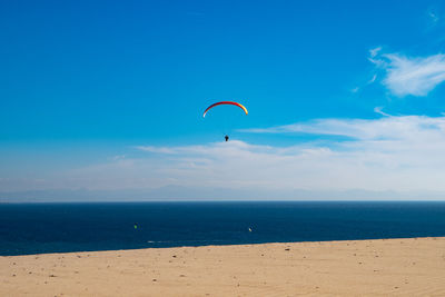Low angle view of person paragliding over sea against sky