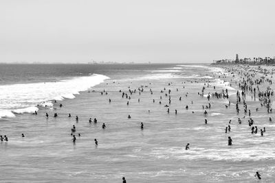 Group of people swimming in sea against sky