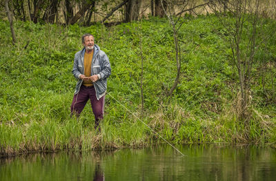 Full length of man standing by lake in forest