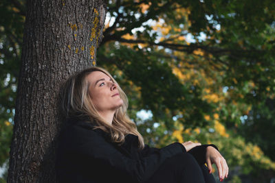 Young woman sitting on tree trunk