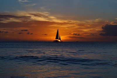 Silhouette sailboat sailing on sea against sky during sunset