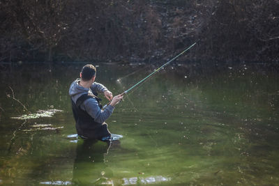 Rear view of man fishing in lake