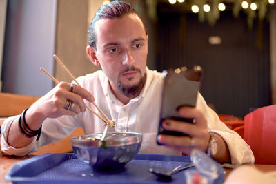 Man using phone while eating food at home