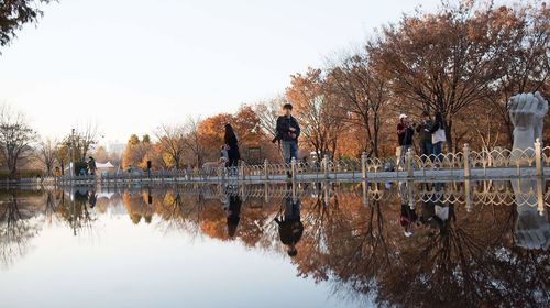 People on lake against clear sky during winter