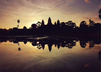 Silhouette trees by lake against sky during sunset