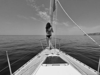 Rear view of woman standing on boat while looking at sea against sky