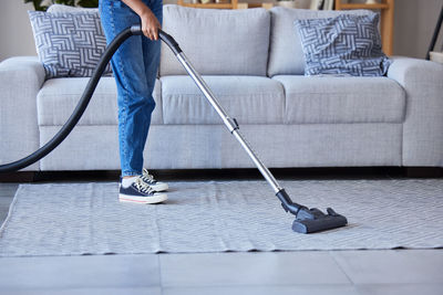 Low section of woman standing on suitcase at home