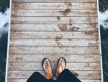 Low section of person standing on wooden floor