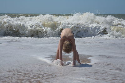 Man splashing water in sea against clear sky