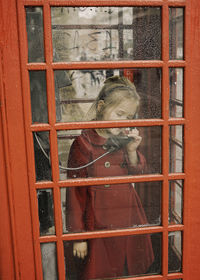 Full length of girl standing in phone booth