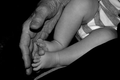 Cropped hand touching baby feet in darkroom