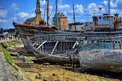 Abandoned boat moored at harbor against sky