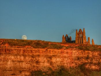 Built structure on rock formation against clear sky