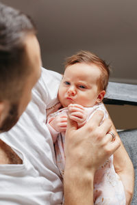 Midsection of father holding daughter while sitting at home