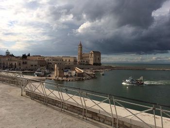 Boats moored in river against cloudy sky