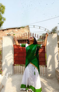 Woman holding umbrella standing against built structure