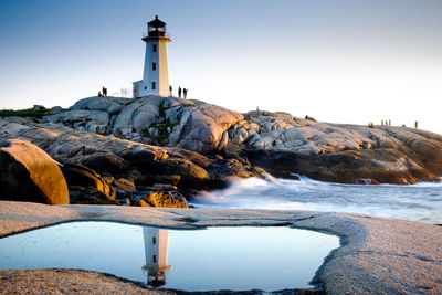 Lighthouse by sea against clear sky