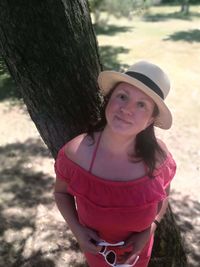 Portrait of smiling woman standing on tree trunk