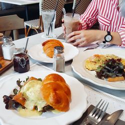 Cropped image of woman holding drink by food on table