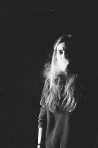 Mid adult woman smoking cigarette at night