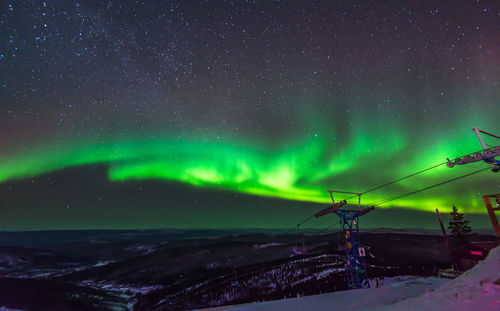 Scenic view of illuminated snowcapped mountains against sky at night