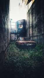 Abandoned car on wall against building