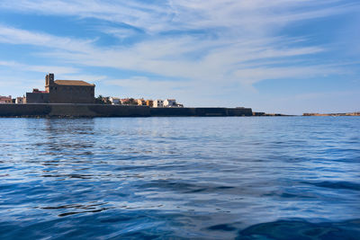 Sea by cityscape against sky