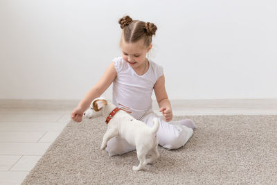 Portrait of smiling woman playing with puppy at home