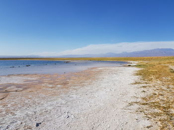 Scenic view of salt lake in desert against blue sky