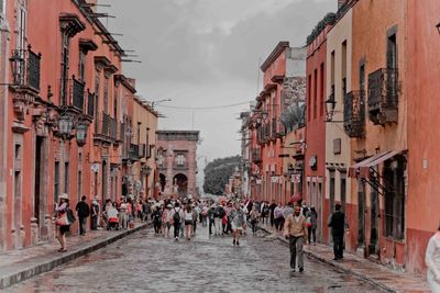 People walking on street amidst buildings in city