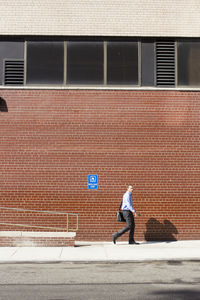 Man walking on footpath against building