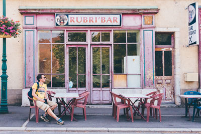 Full length of man sitting on chair against building